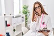 © Krakenimages.com - Young woman wearing doctor uniform talking on the smartphone at clinic
