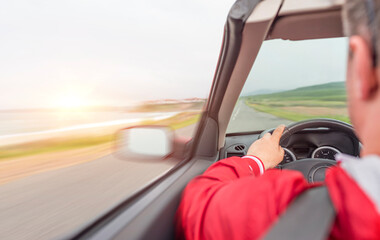 Wall Mural - A man in a red jacket driving a car rushes along the highway.