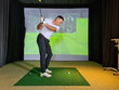 Young man plays golf indoors. Golf simulator