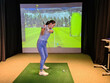 Golfers hitting ball with golf club from indoor court