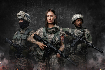 Wall Mural - Portrait of team of three army soldiers dressed in camouflage suits holding rifles.