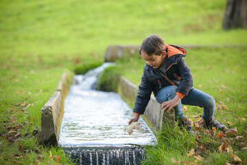 young caucasian boy playing in urban park in autumn