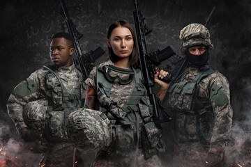 Wall Mural - Portrait of team of three army soldiers dressed in camouflage suits holding rifles.