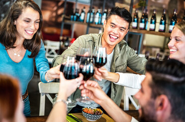 Trendy multicultural friends toasting red wine at sushi poke bowl restaurant - Food and beverage lifestyle concept with happy people having fun together at fusion bar venue - Bright indoor filter