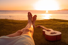 Happy Summer Days. Person Relaxing Feet By The Sea Enjoying Sunset On A  Beach Vacation 