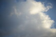 rays of the sun through the cirrus clouds against the blue sky, white rainy clouds blue sky illuminated by the rays of the sun, one small cirrus cloud blurred clouds background