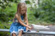 A little girl with long blond hair feeds a white dove in the park