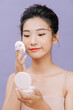 © Marc Tran/Stocksy - Happiness Asian woman applying foundation powder puff on her face