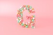 © Bruno Tornielli/Stocksy - Letter G made of glass balls, pastel pearls, crystal jewels and gold.