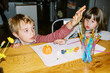© Serena Burroughs/Stocksy - Two children sitting at kitchen table painting pumpkins