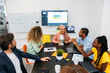 © VICTOR TORRES/Stocksy - Crop cheerful multi coworkers talking at office table