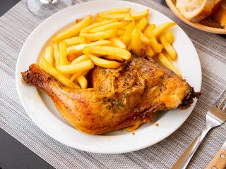 Wall Mural - Appetizing baked chicken leg quarter with browned skin served with crispy fries for dinner..