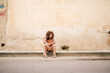 © Daniel Gonzalez/Stocksy - Stylish Cuban woman sitting near old wall