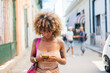 © Daniel Gonzalez/Stocksy - Cuban female texting on cellphone