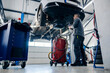 © Dusan Petkovic - A auto-mechanic is using oil suction tool while standing under the car at mechanic's shop.