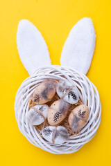 Wall Mural - Easter or spring composition with decorative white wreath, quail eggs and rabbit ears on yellow