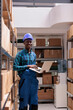 Happy warehouse manager supervising goods storaging and dispatching portrait. Smiling african american storehouse operator holding laptop and checking inventory audit report