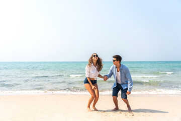 Wall Mural - Vacation romantic love young happy smile couple in honeymoon travel holiday trip standing on sand at blue sky sea beach having fun and relaxing together on tropical beach.Summer travel