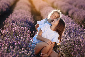 Wall Mural - Happy family in purple lavender field. young beautiful mother and child Girl enjoy walking blooming meadow on summer day. Mom having fun with pretty daughter in nature on sunset. mothers day