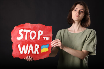 Poster - Sad woman holding poster with words Stop the War on black background