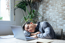 Exhausted Young Caucasian Male Employee Sleep Desk At Office Overwork Preparing Report. Tired Male Fall Asleep Doze Off At Workplace, Work Late To Meet Deadline. Fatigue, Exhaustion Concept..