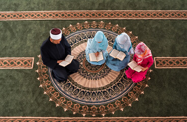 Wall Mural - A Muslim teacher teaches children girls to read a holy book Quran inside the Mosque group of Islamic people praying inside the masjid.	