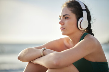 Headphones, fitness and relax woman on beach for wellness, mental health and health in morning sky mockup. Thinking, ideas and calm sports person listening to music or peace podcast by ocean or sea