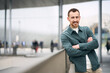 © Maria Vitkovska - Portrait of smiling  handsome modern man with arms crossed looking at camera on the street, copy space. People concept