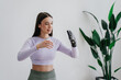 Beautiful European brunette girl in sportswear adjusting hi tech arm prosthesis at home against large plant on background. Orthopaedics and medicine for people after trauma. Hi tech medicine.