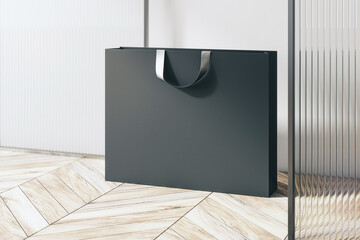 Poster - Perspective view on blank black paper shopping bag with place for your brand name or text on light wooden parquet floor and light wall background, close up. 3D rendering, mockup