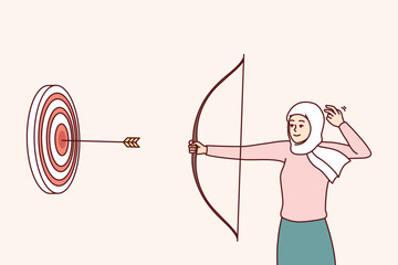 woman in islamic headscarf covering hair shoots at target with arrows hitting middle. girl in hijab 