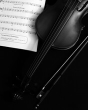 Violin And Bow With Sheet Music On Black Background