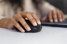 Black woman works on computer. Hands of young adult BIPOC female clicking with modern wireless mouse in close up