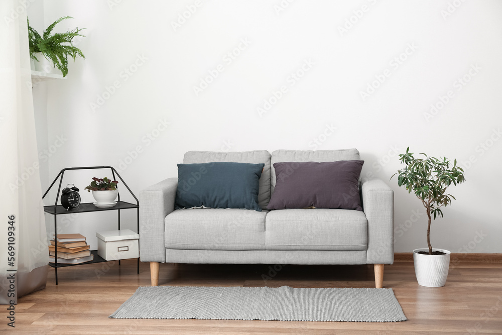 Grey sofa with cushions in interior of light living room