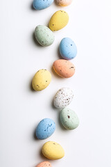 Wall Mural - Easter composition of colorful quail eggs over white background. Springtime holidays concept with copy space. Top view