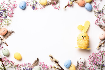 Wall Mural - Beautiful Easter composition with spring flowers, Easter Bunny and colorful quail eggs over white background. Springtime and Easter holiday concept with copy space. Top view