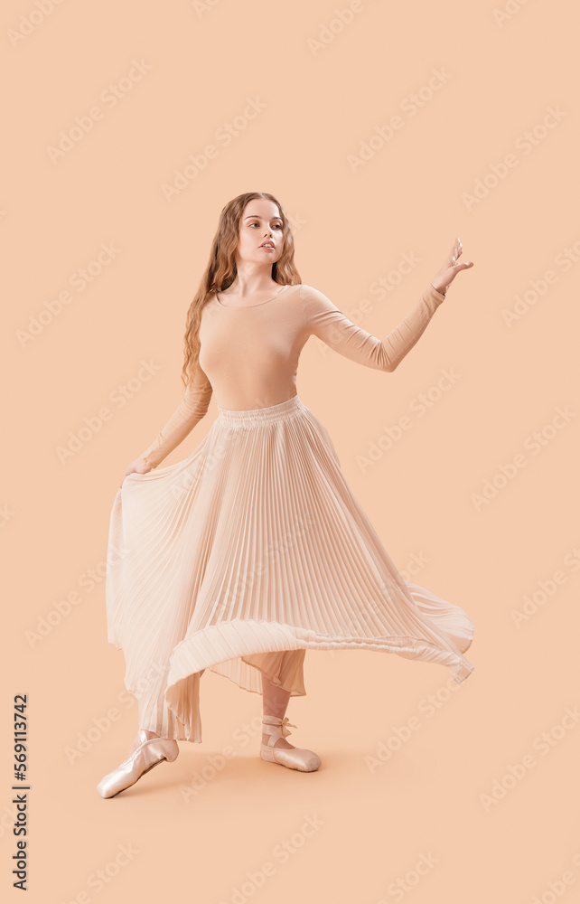 Young ballerina dancing on beige background