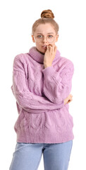 Poster - Young woman in sweater biting nails on white background