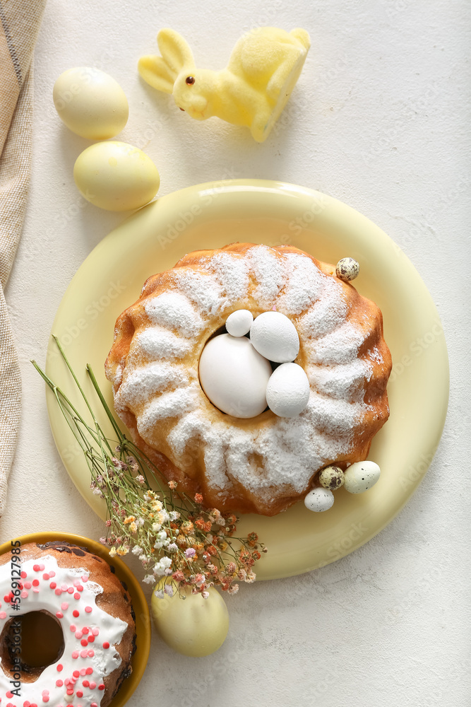 Composition with tasty Easter cakes, painted eggs, gypsophila flowers and bunny on grey table
