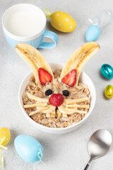 Wall Mural - Cheerful breakfast for children - sweet oatmeal in the shape of rabbit or hare with strawberries, banana and raisins, Easter idea