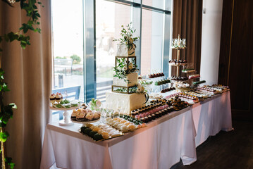 Wall Mural - Delicious wedding reception. Birthday Cake on a background party. Candy bar with wedding cake with flowers for banquet. Celebration concept. Trendy Cake.Table with sweets, candies, dessert.