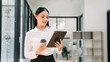© Nuttapong punna - Working woman concept a female manager attending video conference and holding tablet, smatrphone and  cup of coffee in office