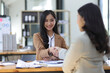© Wasan - Happy businesswomen colleagues discussing in the office, Planning collaboration and participation of people in the organization, handshake, business cooperation.