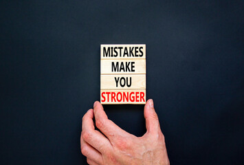 Wall Mural - Mistake make stronger symbol. Concept words Mistakes make you stronger on wooden blocks. Beautiful black table black background. Businessman hand. Business mistake make stronger concept. Copy space.
