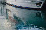 Fototapeta Pomosty - The yacht's side and reflection in the water in the port
