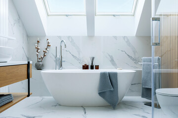 stylish bathroom interior design with marble panels. bathtub, towels and other personal bathroom acc