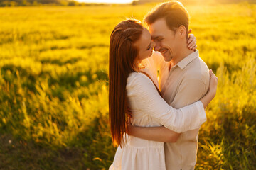 Wall Mural - portrait of cheerful young couple in love standing hugging with closed eyes on beautiful green meado