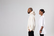 © kanashkin - An african american man in a white hoodie and a woman in a white t-shirt stand on a white background.