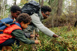 © Maskot - Father picking berries from plants with sons during vacation in forest