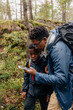 © Maskot - Father using smart phone with son while exploring forest during vacation